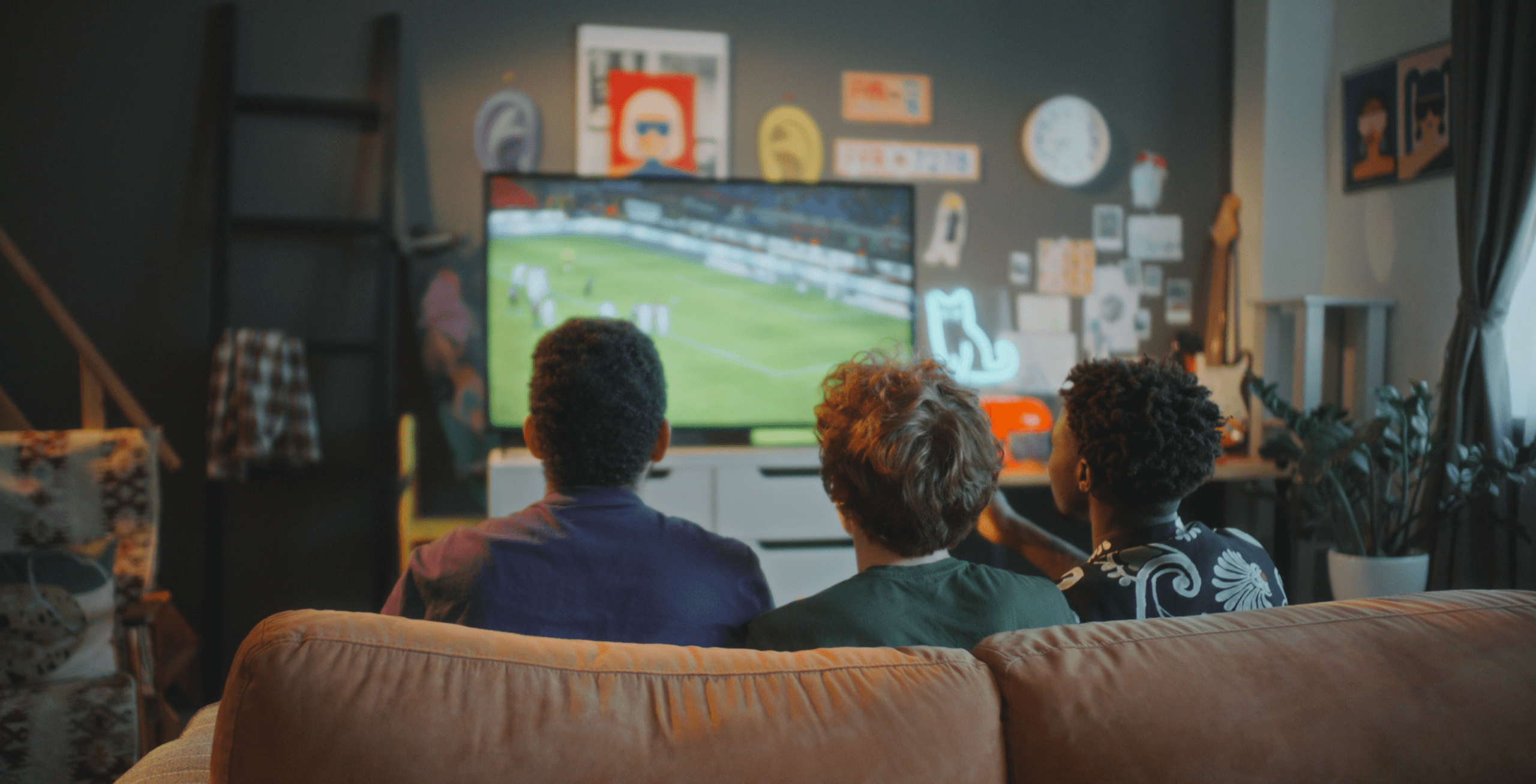Teens sitting on a couch watching soccer